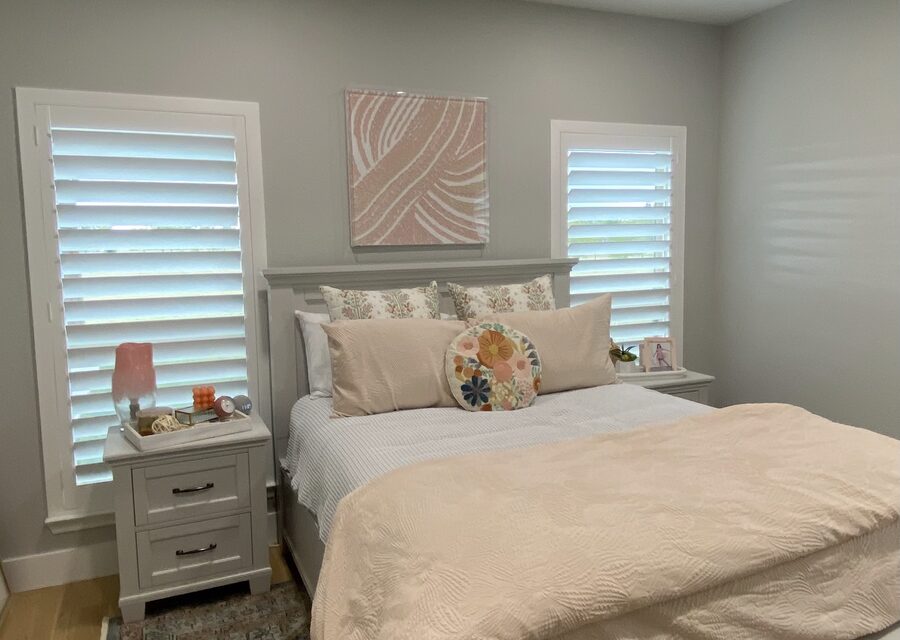 Real hardwood interior shutters framing a DFW bedroom window in warm daylight